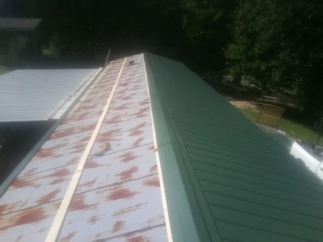 Old rusted panels beside newly installed green metal roofing — Wind Damage Roof Repair by Roofing Brothers in Yorktown Heights