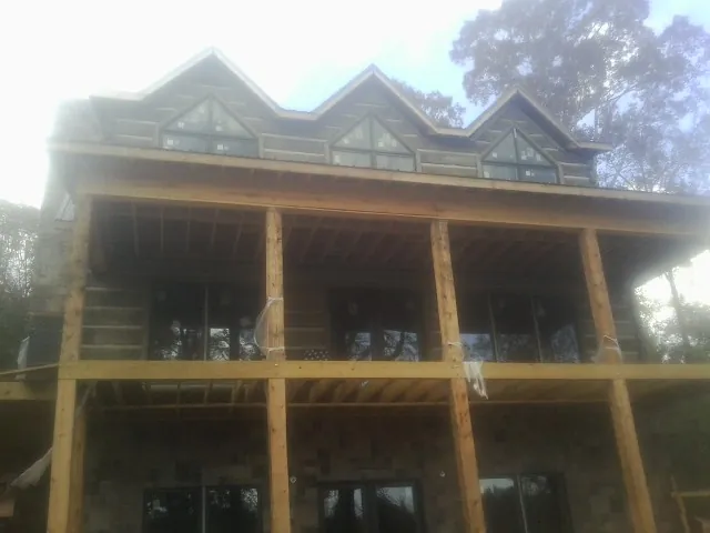 Dormers and porch framing on a large log home under construction — Roof Coating work by our crew in Yorktown Heights