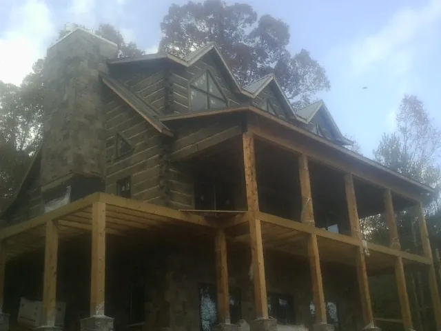 Stone chimney and dormers on a large log home with a timber porch in Yorktown Heights