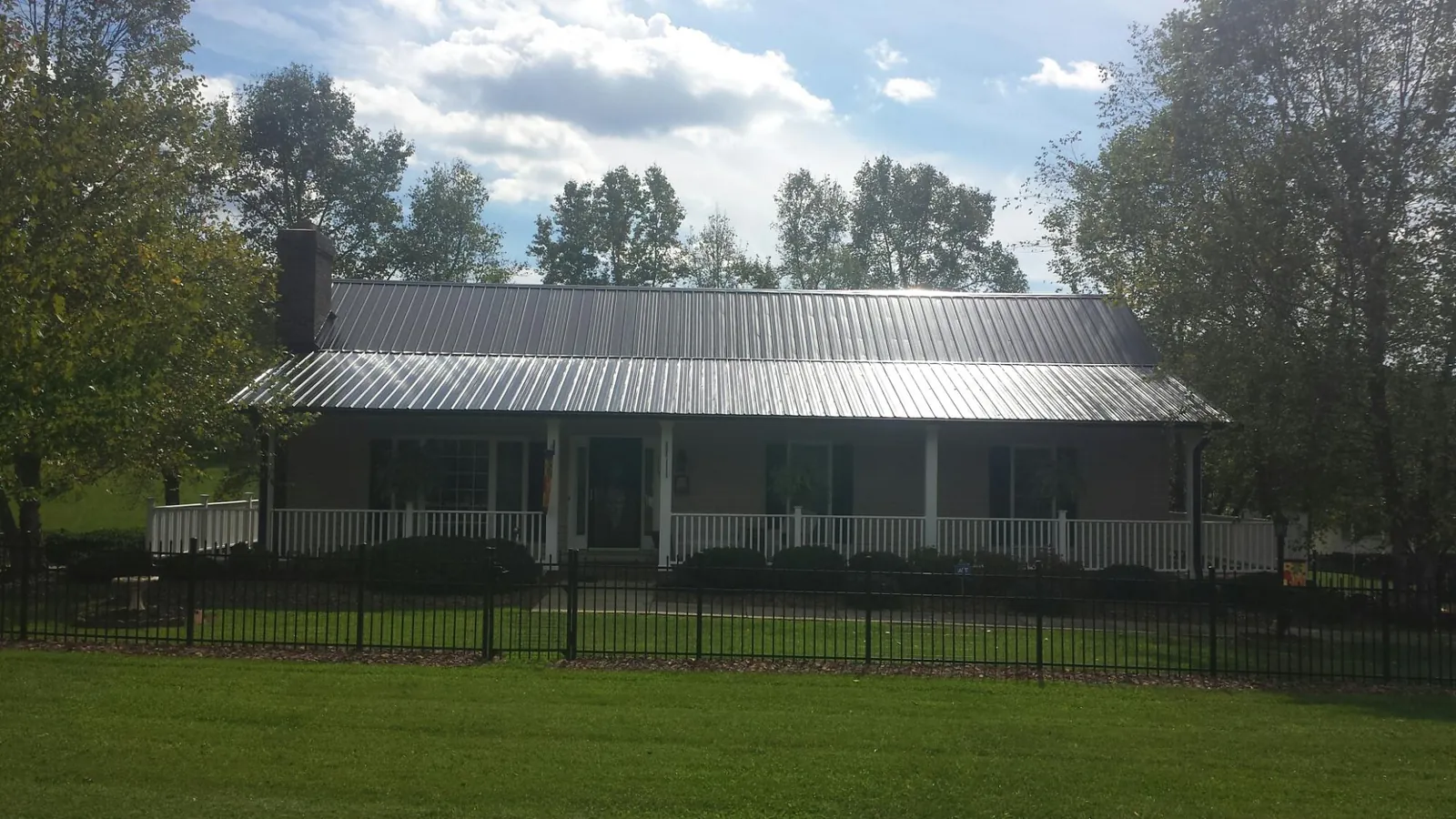Gray metal roof on a brick ranch with a full width front porch — Gutter Guard Installation work by our crew in Yorktown Heights