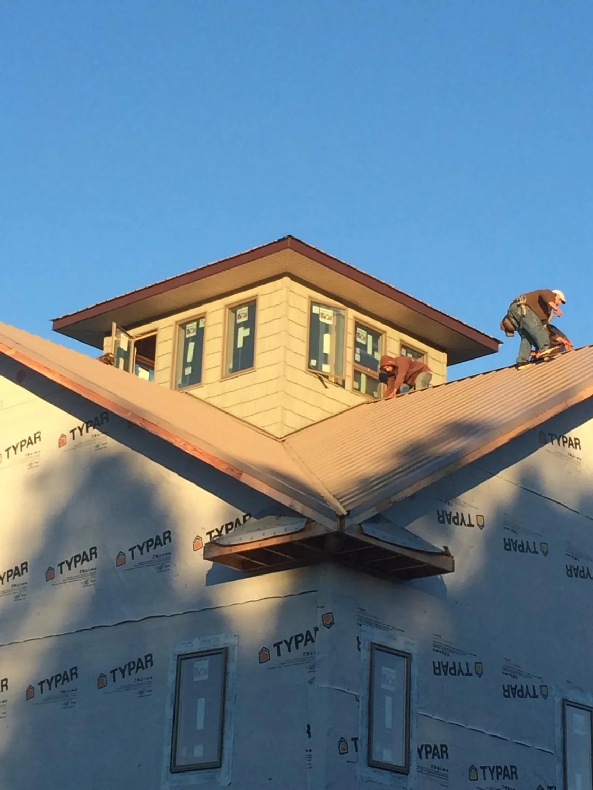 Roofers working around a rooftop cupola on a new metal roof at sunset — Roof Waterproofing in Yorktown Heights by Roofing Brothers